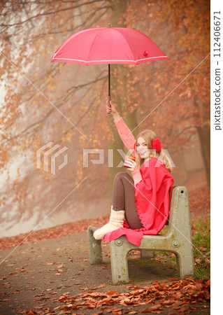 Girl in autumn park enjoying hot drink 112406671