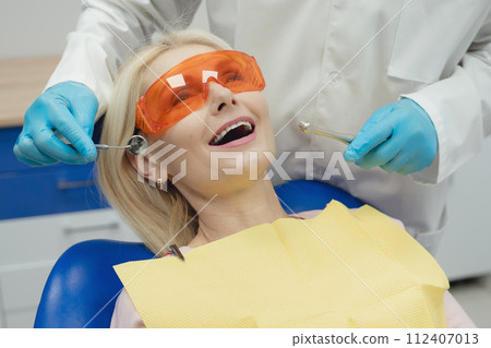 Woman smiling during her dental treatment at dentist. Woman smiling during her dental treatment at dentist. 112407013