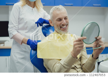 Male smiling during her dental treatment at dentist. Male smiling during her dental treatment at dentist. 112407053