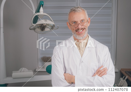 Portrait of attractive handsome dentist with haircut, white lab coat. 112407078