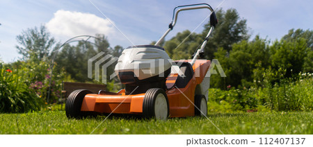 A lawnmower at the meadow, in the backyard lawn. 112407137