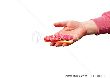 Sandwich with sausage in the hand of a middle-aged woman. The concept of the world food crisis associated with the war in Ukraine. Isolated on white background Sandwich with sausage in the hand of a middle-aged woman. The concept of the world food crisis associated with the war in Ukraine. Isolated on white background 112407180