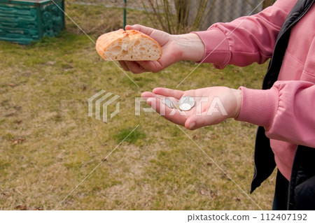 Last money for bread. Bread in the hand of a middle-aged woman. The concept of the world food crisis associated with the war in Ukraine Last money for bread. Bread in the hand of a middle-aged woman. The concept of the world food crisis associated with the war in Ukraine 112407192