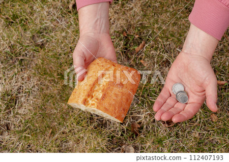 Last money for bread. Bread in the hand of a middle-aged woman. The concept of the world food crisis associated with the war in Ukraine 112407193