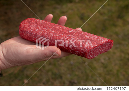 Sausage in the hand of a middle-aged woman. The concept of the world food crisis associated with the war in Ukraine 112407197