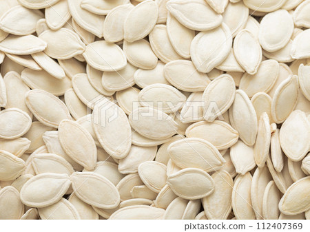 Raw white salted pumpkin seeds top view macro background. Raw white salted pumpkin seeds top view macro background. 112407369