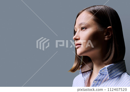 Profile portrait of young serious woman on grey background Profile portrait of young serious woman on grey background 112407520