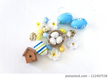 Happy easter holidays concept; Easter eggs, birdnest with eggs and flowers on a white background; top view Happy easter holidays concept; Easter eggs, birdnest with eggs and flowers on a white background; top view 112407536