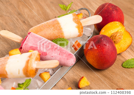 Homemade raspberries and peach popsicles 112408398