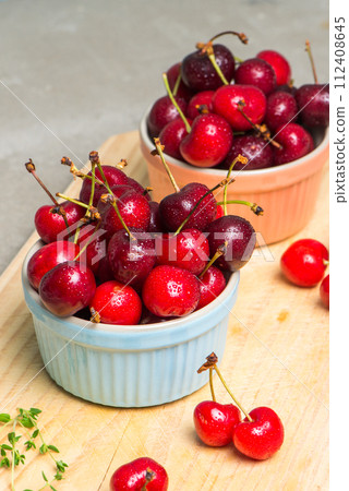 Red ripe cherries in ceramic bowls 112408645