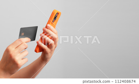 Berlin Germany January 21 2024 Hand using finance mobile app and bank credit card. Banner background Berlin Germany January 21 2024 Hand using finance mobile app and bank credit card. Banner background 112408674