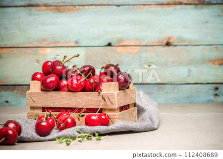Red ripe cherries in small wooden box 112408689