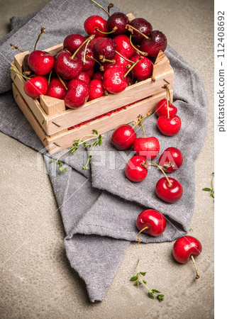 Red ripe cherries in small wooden box 112408692