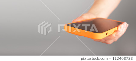 Hand holding mobile phone, smartphone, cellphone closeup. Banner background, copy space for text 112408728