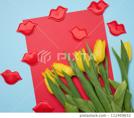Bouquet of blooming yellow tulips with green leaves on a blue background Bouquet of blooming yellow tulips with green leaves on a blue background 112409632