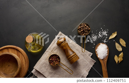 Salt, allspice, peppercorns and olive oil in a bottle on a black table Salt, allspice, peppercorns and olive oil in a bottle on a black table 112409751