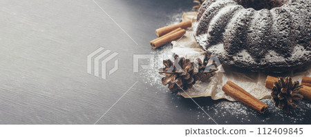 Christmas cake with chocolates and spices, cinnamon, dried fruits. Sprinkled with powdered sugar. Christmas cake with chocolates and spices, cinnamon, dried fruits. Sprinkled with powdered sugar. 112409845