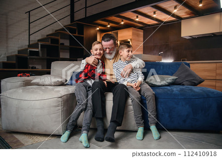 Likable concentrated senior bearded grandfather with his cheerful 10-15s grandsons spending their free time at revision the basketball game on tv Likable concentrated senior bearded grandfather with his cheerful 10-15s grandsons spending their free time at revision the basketball game on tv 112410918