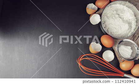 Baking background with flour, eggs, kitchen tools, utensils  on dark table. Top view.  Mock up. 112410941