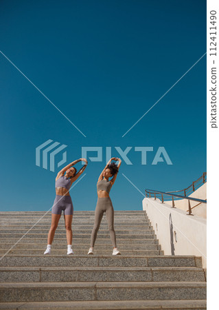 Young sportswomen in tracksuit are stretching outdoor and preparing to jogging. Healthy life concept Young sportswomen in tracksuit are stretching outdoor and preparing to jogging. Healthy life concept 112411490