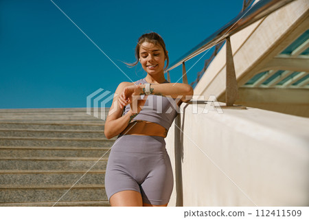 Smiling fit woman looking at smartwatch and counting calories burned. Healthy life concept 112411509