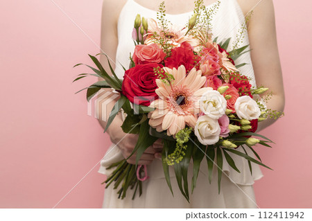 Cropped Woman Holds Beautiful Fresh Bouquet Of Flowers For Wedding Or Occasion On Pink Background. Colorful Mixed Roses, Carnation Shabot, Green Leaves, Gerber. Horizontal Plane 112411942