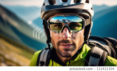 Man wearing helmet and sunglasses glasses stands confidently before towering mountain backdrop ready for adventure, exploration. He may be gearing up for bicycle ride, some other outdoor activity. Man wearing helmet and sunglasses glasses stands confidently before towering mountain backdrop ready for adventure, exploration. He may be gearing up for bicycle ride, some other outdoor activity. 112412104