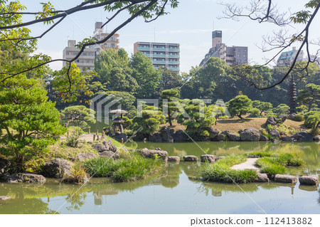 [Japan] Tokyo, a modern building seen through the pond and pine trees of Kiyosumi Garden 112413882