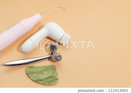 Flatly Mockup Skin Care Products. Facial Tool Gua Sha, Darsonval Skin Beauty Device, Sculpt Facial Roller, Anti-Aging, Facial Cleansing Brush on Beige Background. Copy Space For Text. Horizontal Plane 112413903