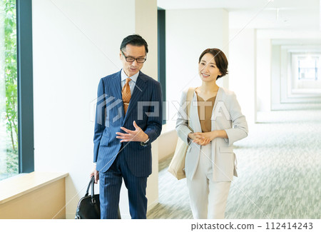 走在辦公室走廊的中年商務人士 走在辦公室走廊的中年商務人士 112414243