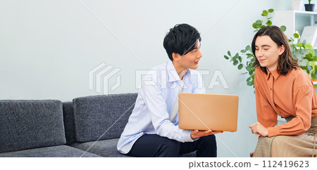 跨國人士在大廳一邊看著筆記型電腦一邊交談 112419623