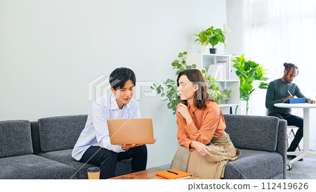 跨國人士在大廳一邊看著筆記型電腦一邊交談 112419626