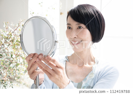 Beauty Woman holding a mirror by the window 112419788