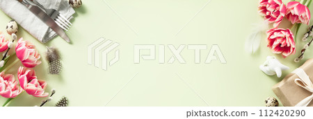 Easter table setting with spring flowers and cutlery on green background top view flat lay 112420290