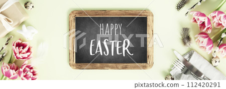 vintage chalk board, spring flowers and cutlery on green background 112420291