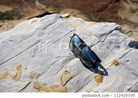 [Minamichita] Sunglasses placed on a rocky area on the coast 112420330