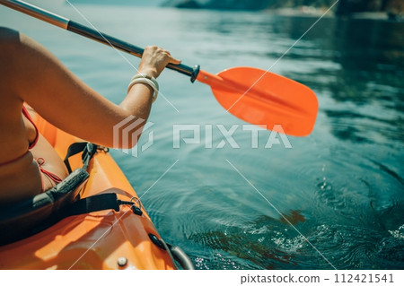 Kayak paddle sea vacation. Person paddles with orange paddle oar on kayak in sea. Leisure active lifestyle recreation activity rest tourism travel Kayak paddle sea vacation. Person paddles with orange paddle oar on kayak in sea. Leisure active lifestyle recreation activity rest tourism travel 112421541