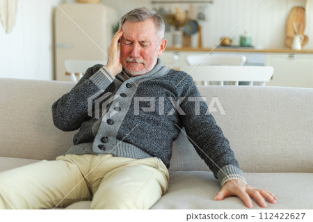 Headache pain. Unhappy middle aged senior man suffering from headache sick rubbing temples at home. Mature old senior grandfather touching temples experiencing stress. Man feeling pain hurt in head Headache pain. Unhappy middle aged senior man suffering from headache sick rubbing temples at home. Mature old senior grandfather touching temples experiencing stress. Man feeling pain hurt in head 112422627