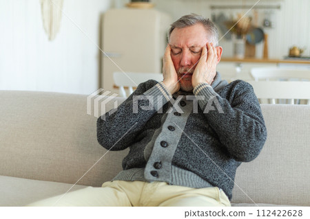 Headache pain. Unhappy middle aged senior man suffering from headache sick rubbing temples at home. Mature old senior grandfather touching temples experiencing stress. Man feeling pain hurt in head Headache pain. Unhappy middle aged senior man suffering from headache sick rubbing temples at home. Mature old senior grandfather touching temples experiencing stress. Man feeling pain hurt in head 112422628