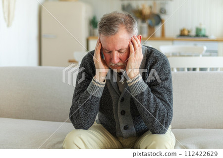 Headache pain. Unhappy middle aged senior man suffering from headache sick rubbing temples at home. Mature old senior grandfather touching temples experiencing stress. Man feeling pain hurt in head 112422629