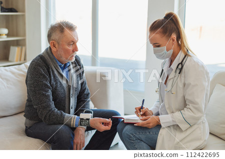 Female doctor senior man taking his blood pressure in doctor office or at home. Old man patient and doctor have consultation in hospital room. Medicine healthcare medical checkup. Visit to doctor Female doctor senior man taking his blood pressure in doctor office or at home. Old man patient and doctor have consultation in hospital room. Medicine healthcare medical checkup. Visit to doctor 112422695