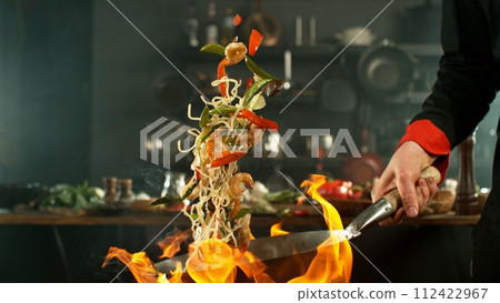 Freeze motion of flying asian wok noodles with prans and vegetable. The concept of meat preparation. Freeze motion of flying asian wok noodles with prans and vegetable. The concept of meat preparation. 112422967