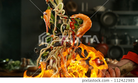 Freeze motion of flying asian wok noodles with prans and vegetable. The concept of meat preparation. Freeze motion of flying asian wok noodles with prans and vegetable. The concept of meat preparation. 112422985