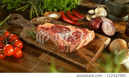 A view of a fresh raw beef steak on a wooden board placed on the kitchen counter. The concept of meat preparation. 112422995