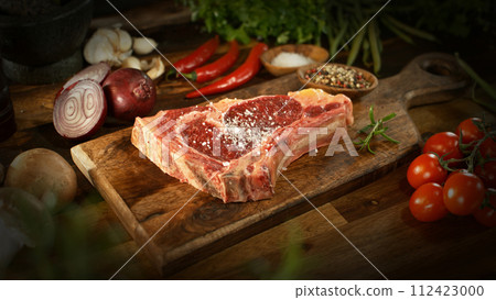 A view of a fresh raw beef steak on a wooden board placed on the kitchen counter. The concept of meat preparation. 112423000