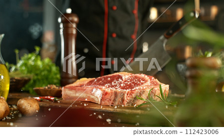 A view of a fresh raw beef steak on a wooden board placed on the kitchen counter. The concept of meat preparation. 112423006