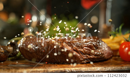 Close-up of falling salt on tasty beef steak in kitchen. 112423032