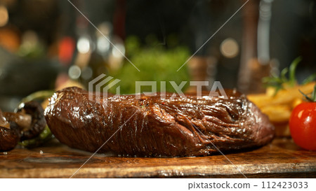 A view of a fresh beef steak on a wooden board placed on the kitchen counter. The concept of meat preparation. 112423033