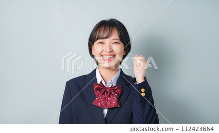 A female student wearing a uniform doing a fist pump 112423664