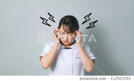 A woman wearing a white coat holding her head and worrying 112423701